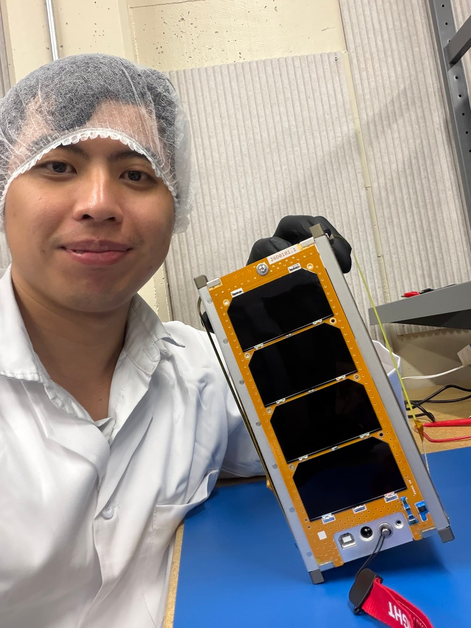 Ken in cleanroom garb holding the KENSAT flight unit